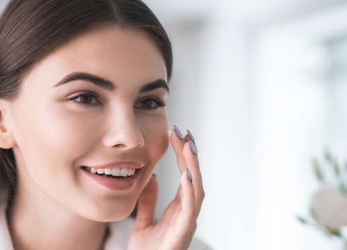 Woman looking at her face in the mirror after chemical peels